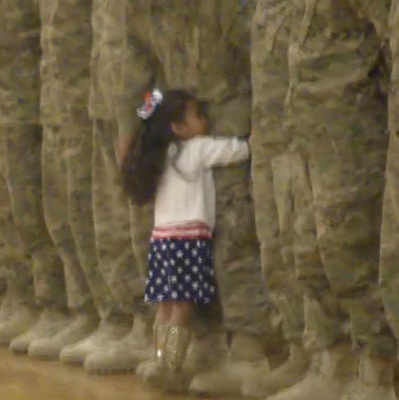 A little girl interrupts the troop's homecoming celebration to give her father a hug