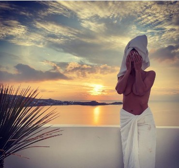 Heidi Klum, 48, wears nothing but a towel while taking in the sunrise on the beach